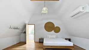 Ein Schlafzimmer mit einem hölzernen Bett, einer Pendelleuchte, einer Wand-Klimaanlage und einer Tür, die auf einen Balkon führt.