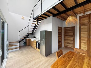 Een moderne keuken met een inbouwkoelkast, houten keukenkastjes, en een eethoek met een houten tafel en stoelen.