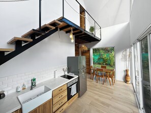 Een moderne keuken met een inbouwoven, een koelkast, en een eethoek met een tafel en stoelen.