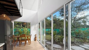 Eine moderne Küche mit Essbereich und großen Schiebeglastüren, die zu einem Garten führen.