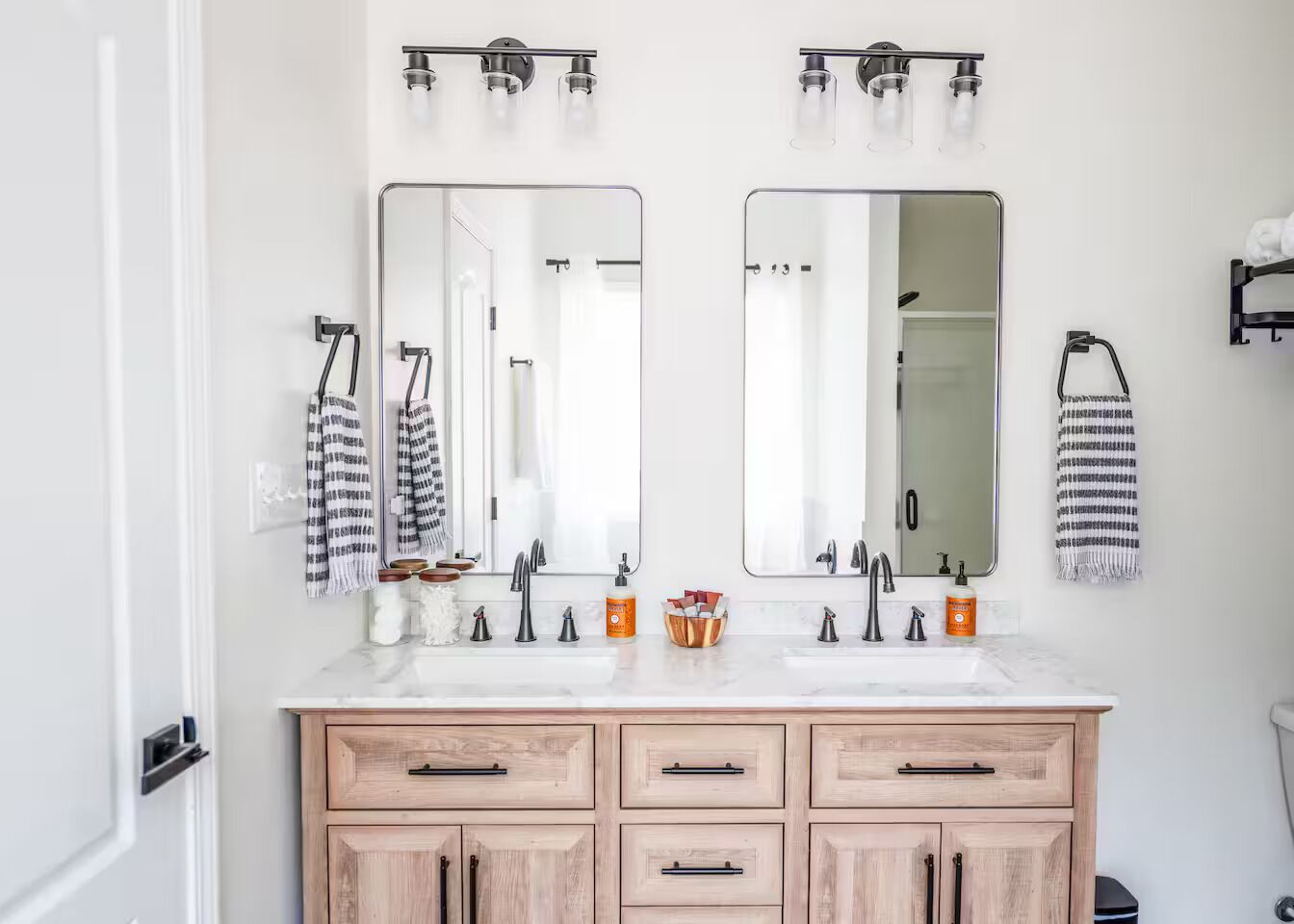 A bathroom with two sinks, wooden cabinets, and a mirror above each sink.