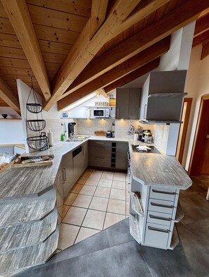 Eine moderne Küche mit Holzbalken, einer Mikrowelle und einem Spülbecken.