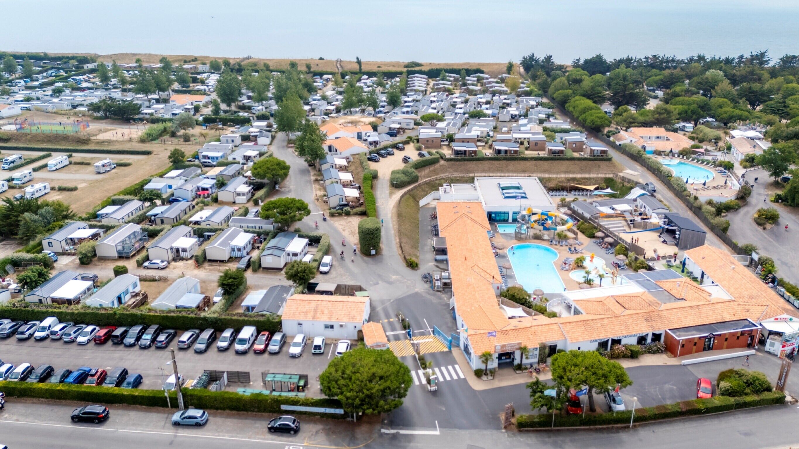 Ein Caravanpark mit mehreren Stellplätzen für Wohnwagen, einem Schwimmbad und einem Parkplatz.
