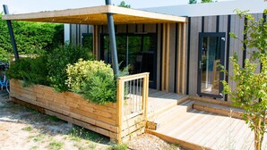 En modern byggnad med ett trädäck, en täckt uteplats och en entré med glasdörr.