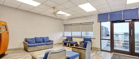 A room with wicker furniture, a ceiling fan, and a view through a glass door.
