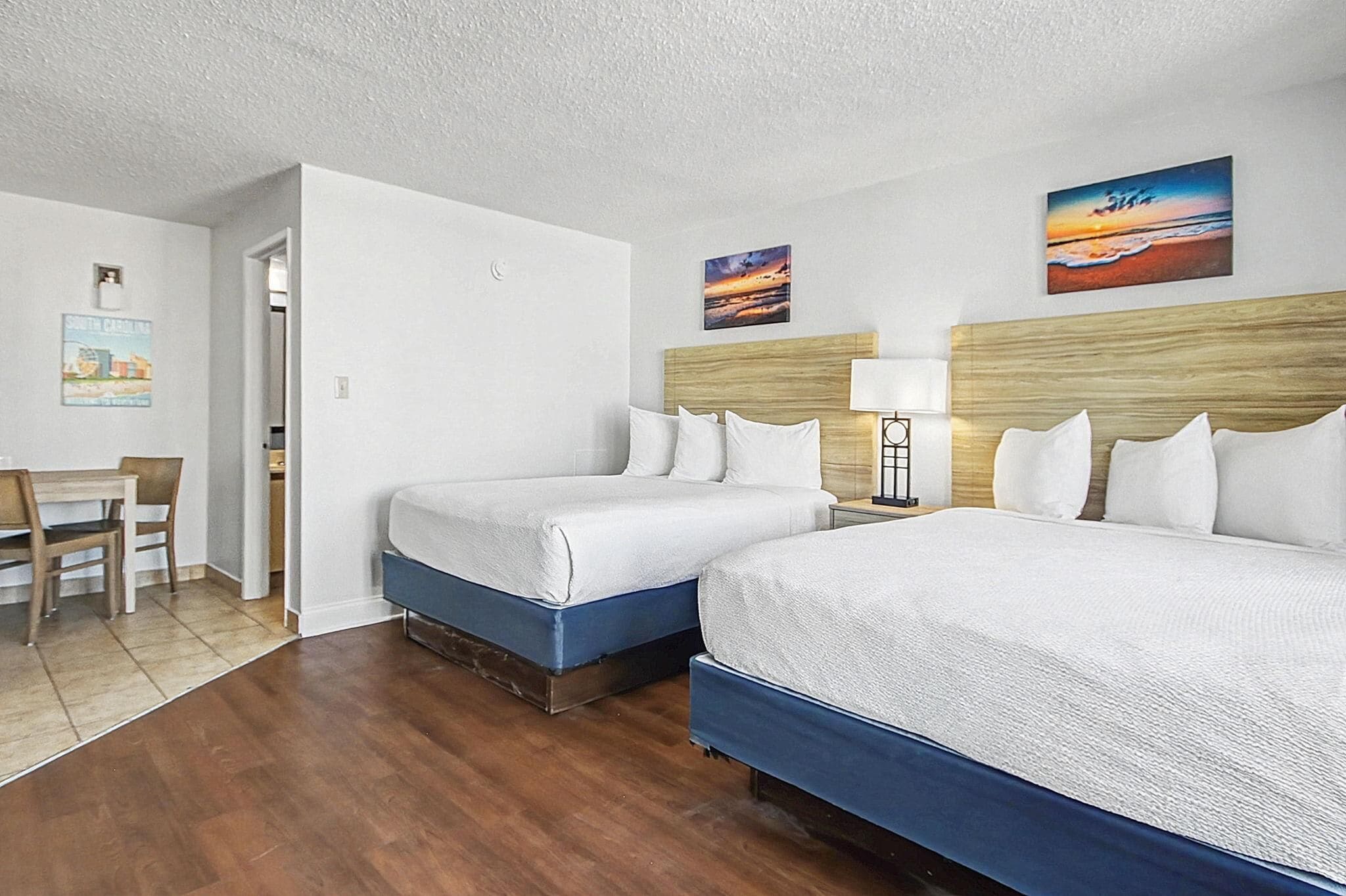A hotel room with two beds, a desk, and a chair.