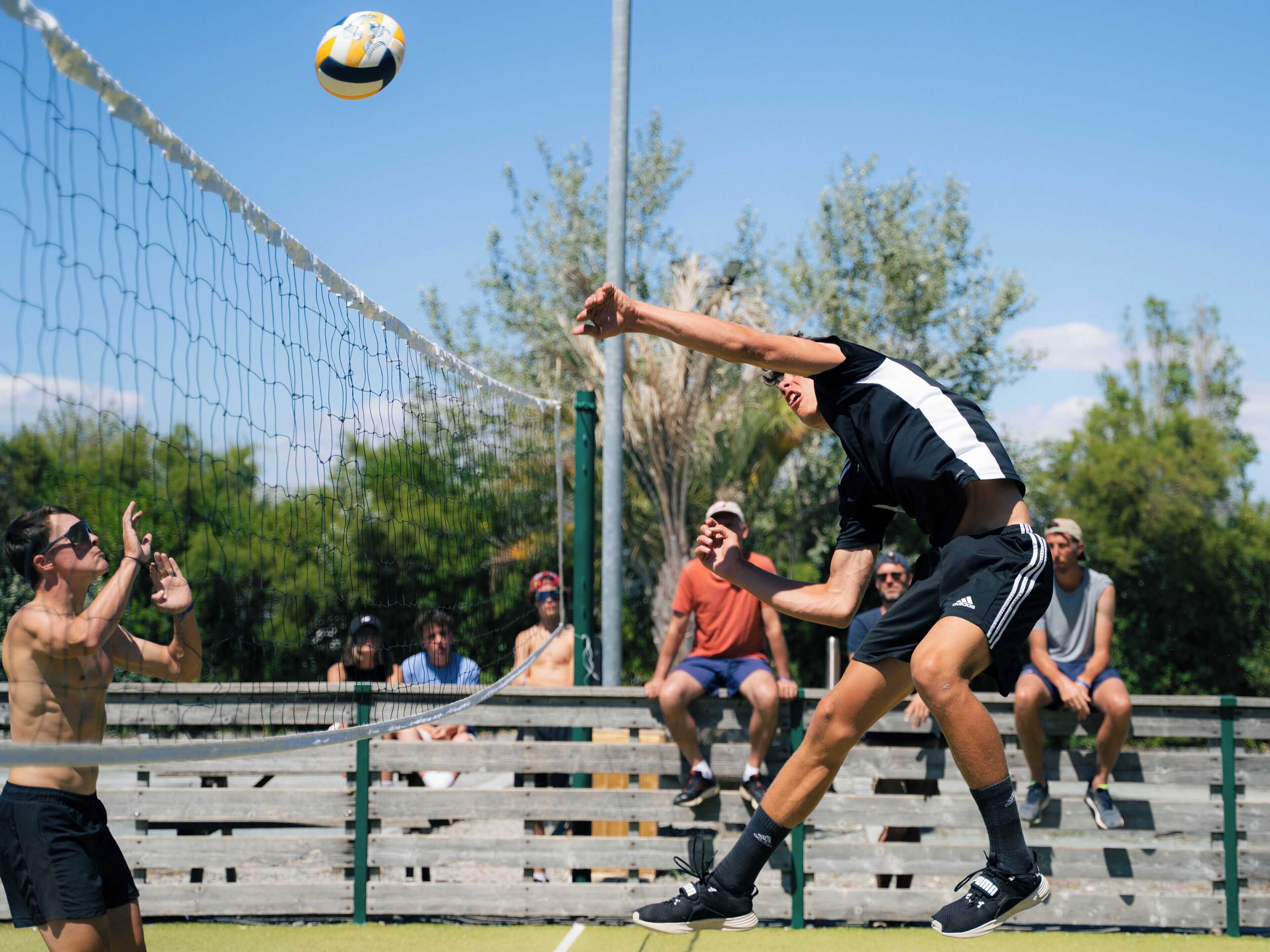 Partido de voleibol en desarrollo, con jugadores y espectadores.