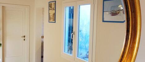 Una habitación con suelo de madera, una puerta blanca y una ventana que ofrece vistas al exterior.