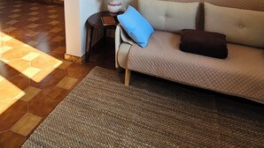 A living room with a beige sofa, a blue pillow, and a brown pillow. There are three framed pictures on the wall. A lamp is on a side table next to the sofa. - Attic room a stone's throw from the harbor. Private parking. (Livorno)