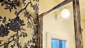 A bathroom with a shower area, a door with a frosted glass window, and a wall with a floral pattern. - Attic room a stone's throw from the harbor. Private parking. (Livorno)