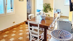 A dining area with a hexagonal tiled floor, a wooden table, white chairs, a hanging light fixture, and a view of the kitchen and living area through an open doorway. - Attic room a stone's throw from the harbor. Private parking. (Livorno)