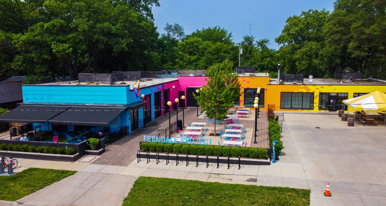 Un espace extérieur agrémenté de sièges colorés, avec un bâtiment bleu, rose et jaune en arrière-plan.