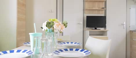 Un comedor con una mesa dispuesta para dos personas, con platos a rayas y un florero con flores.
