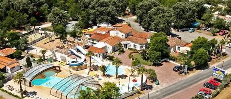 An aerial view of a resort with a swimming pool, water slides, and a covered area.