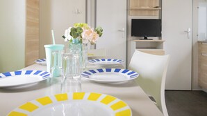Un comedor con una mesa dispuesta para dos personas, con platos a rayas y un florero con flores.