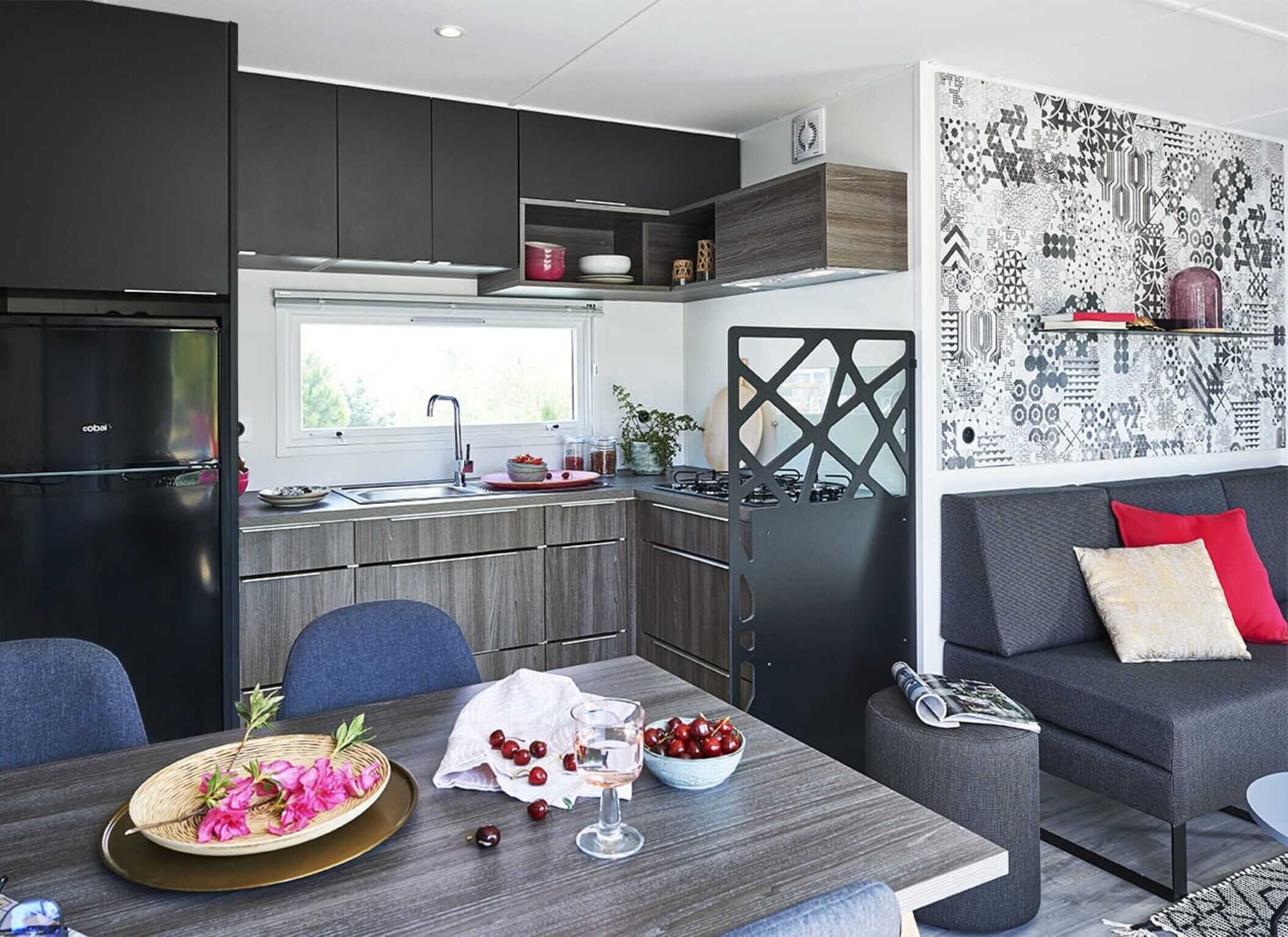 A modern kitchen with dark cabinetry, a built-in stove, and a window above the sink.