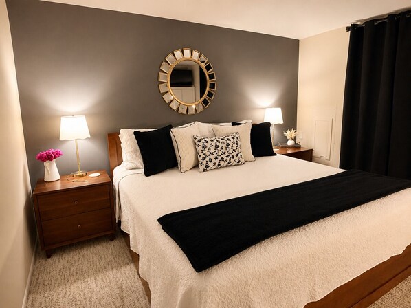 A hotel room with a bed, two bedside tables with lamps, a mirror, and a dresser.