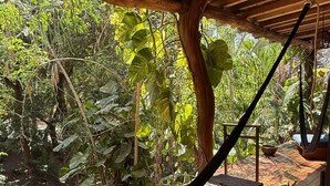 A hammock under a wooden structure with a view of lush greenery. - AC Room with Balcony and Nature Views (Santa María Tonameca)