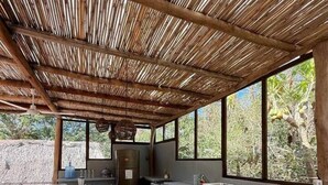 An outdoor kitchen area with a concrete floor, a counter, and a thatched roof. - Loft with Balcony and Nature Views (Santa María Tonameca)
