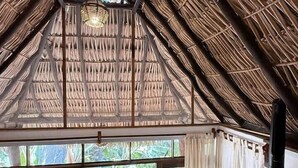 A room with a thatched roof, wooden beams, and a large window with curtains. - Loft with Balcony and Nature Views (Santa María Tonameca)