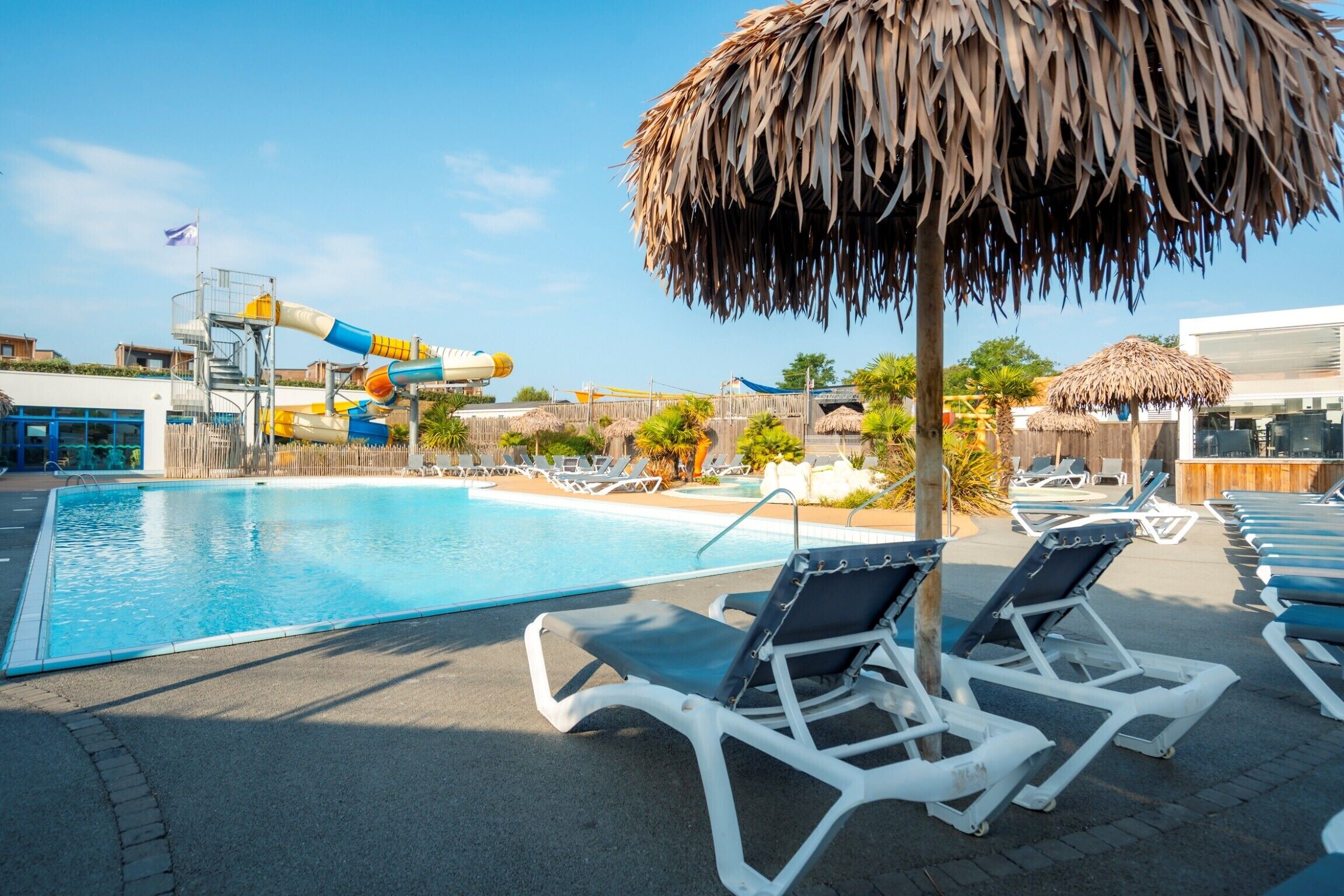 A swimming pool with lounge chairs and a water slide.