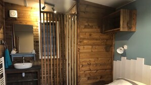 A bedroom with a wooden wall, a white bed, a bathroom with a sink and mirror, and a wooden cabinet. - Carva - Privilège 3 - 6p (3) (La Guérinière)