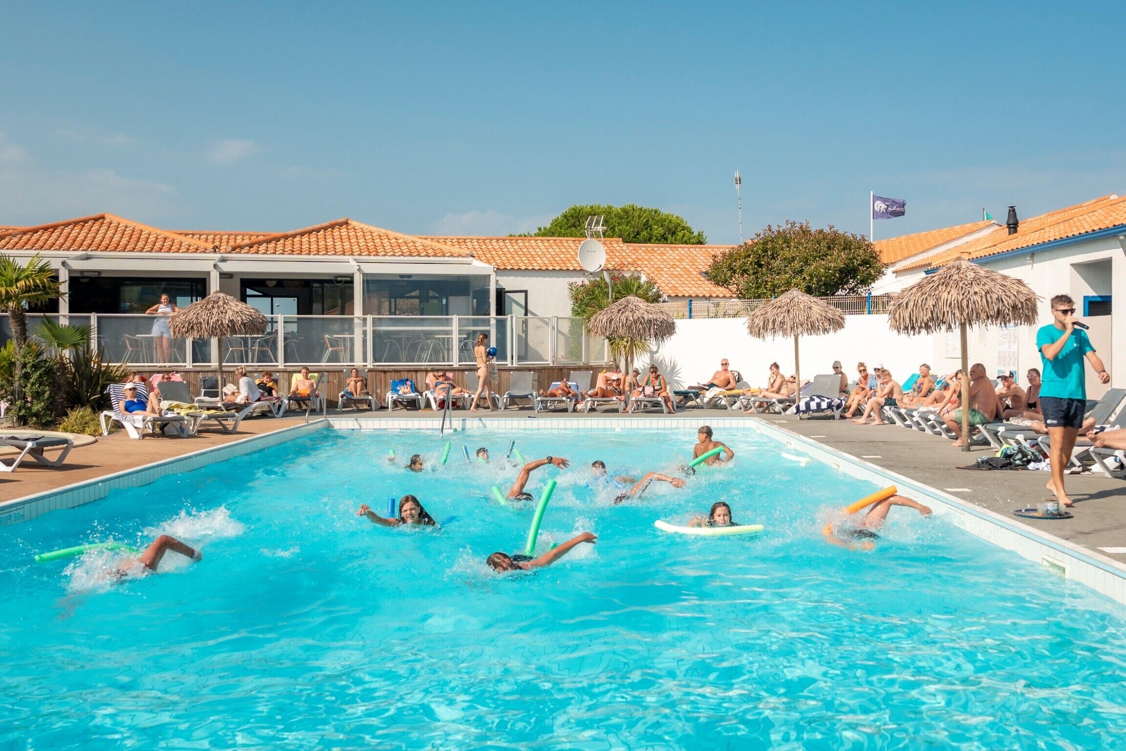 A swimming pool area with people swimming and lounging.