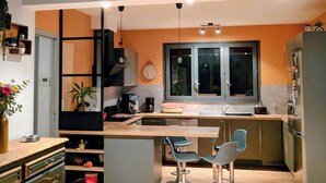 Cozinha moderna com ilha central, banquetas e geladeira.