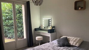 Quarto com cama, escrivaninha com espelho e vista para o verde lá fora.