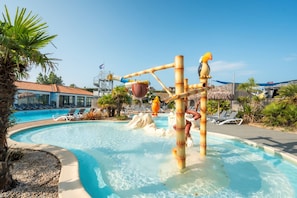 Una piscina con tobogán de agua, sillas de descanso y palmeras.