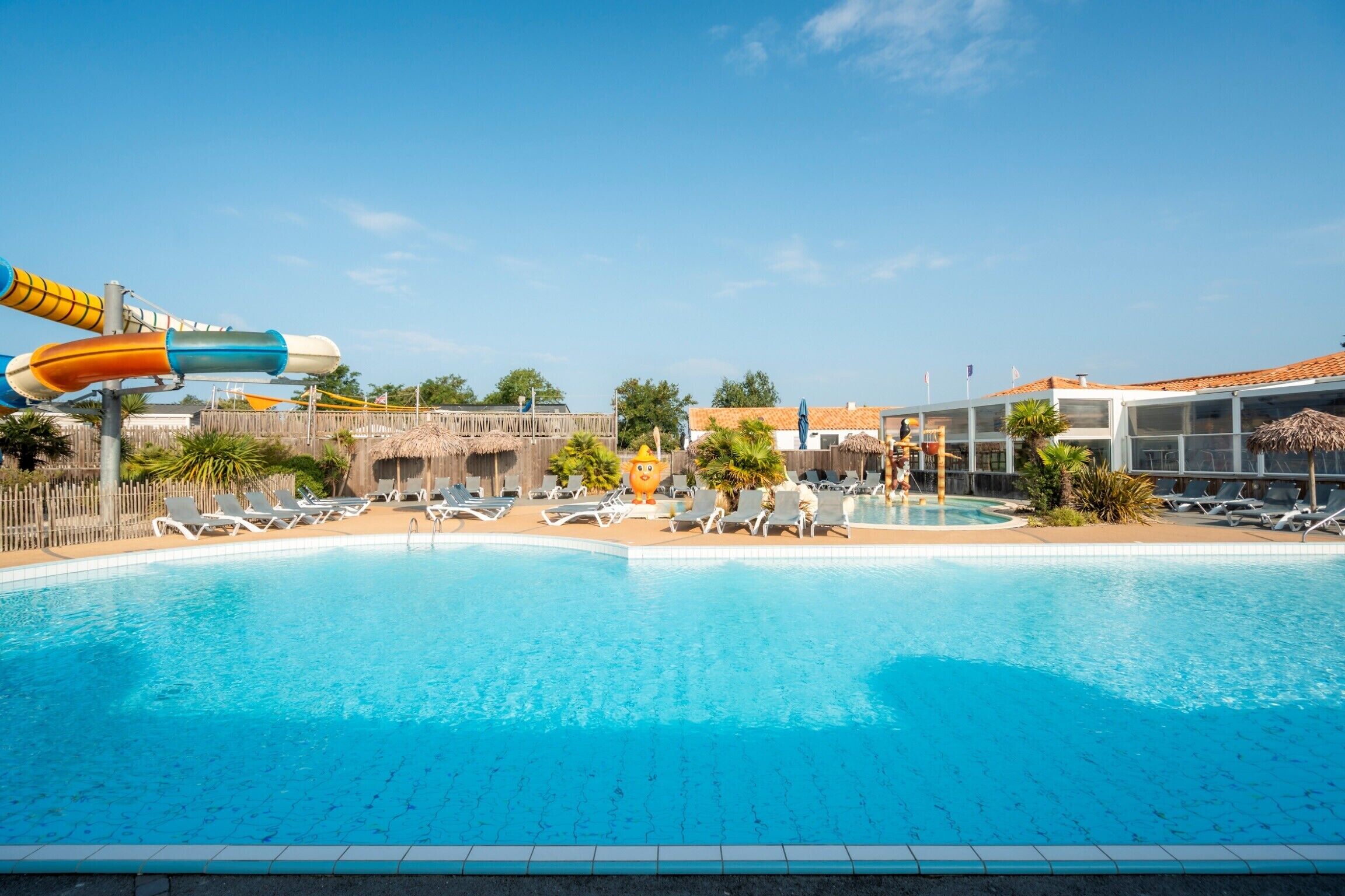 A swimming pool with water slides, lounge chairs, and a building with a tiled roof.