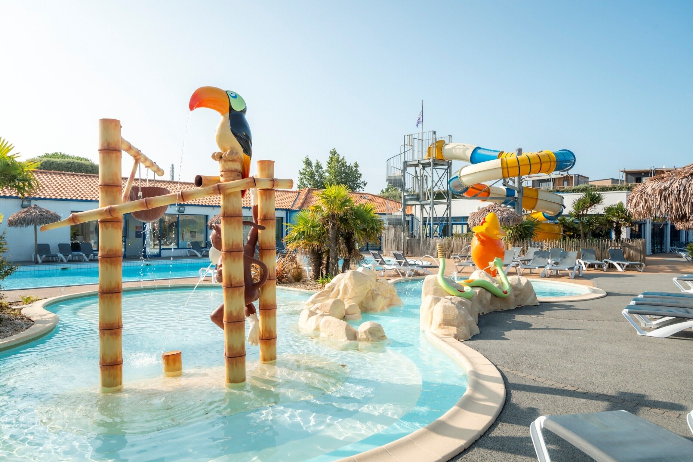 A water park with slides and a pool area, including lounge chairs and palm trees.