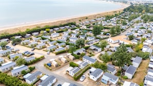 Ein großer Caravanpark mit zahlreichen Mobilheimen, einem Strand im Hintergrund und einem klaren Himmel.
