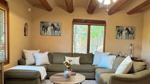 A living room with a sectional sofa, a coffee table, and artwork on the walls. - Horse Ranch Casita #B (Santa Fe)