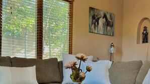 A living room with a sofa, a round coffee table, and a vase with flowers. - Horse Ranch Casita #B (Santa Fe)