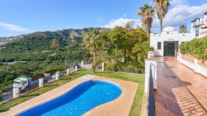 A swimming pool with a view of a hilly landscape, a white building with a dome, and a fenced area with a truck.