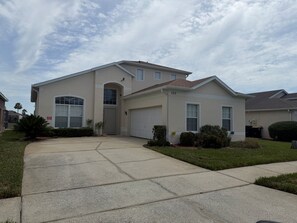 Ein zweistöckiges Haus mit Garage, Auffahrt und einem gepflegten Rasen.
