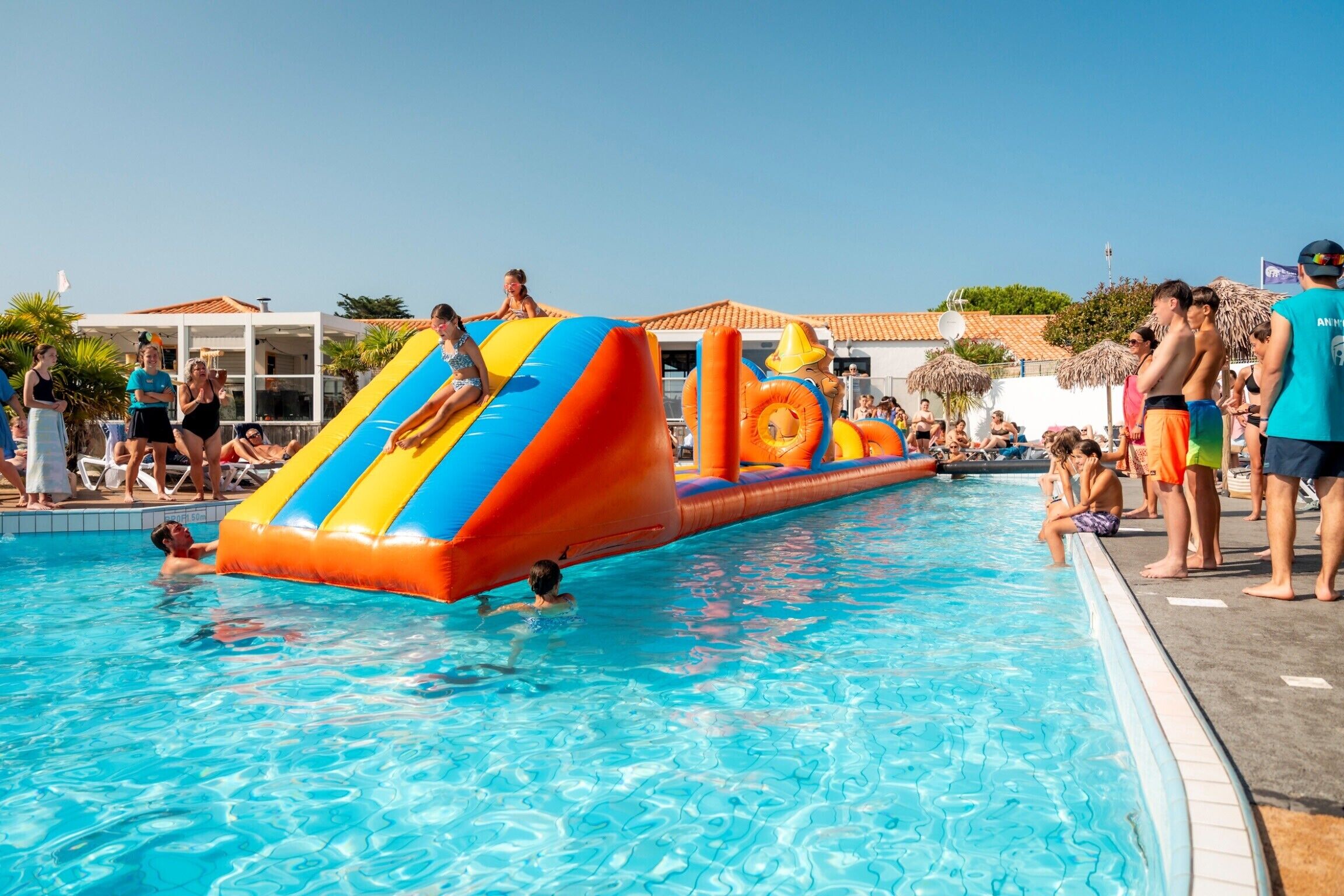 A swimming pool with inflatable slides and a lounge area with sun loungers.