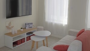 A modern living room with a flat-screen TV, a white sofa, a small round table, and a wooden ceiling beam. - La Forge by L'Ora, a haven of peace 2 steps from the center of Cassel (Cassel)