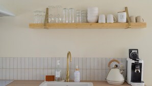 A kitchen with a white sink, wooden countertop, and a shelf above holding glassware and mugs. - La Forge by L'Ora, a haven of peace 2 steps from the center of Cassel (Cassel)