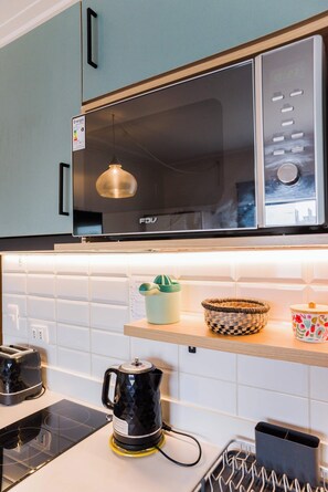A kitchen with a microwave, toaster, kettle, and a window above the counter.
