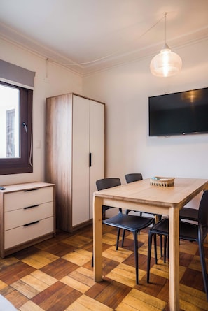 A room with a wooden dining table, black chairs, a TV mounted on the wall, and a wardrobe. - Comfortable Apartment with Full Kitchen and Wifi (Providencia)