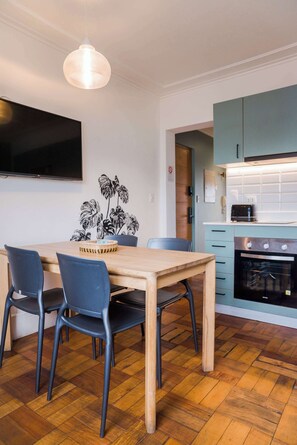 A modern kitchen with a wooden table, chairs, a TV, and a built-in oven.