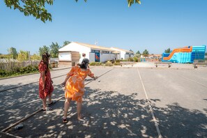 Un espace extérieur comprenant un bâtiment, une aire de jeux et un ciel dégagé.