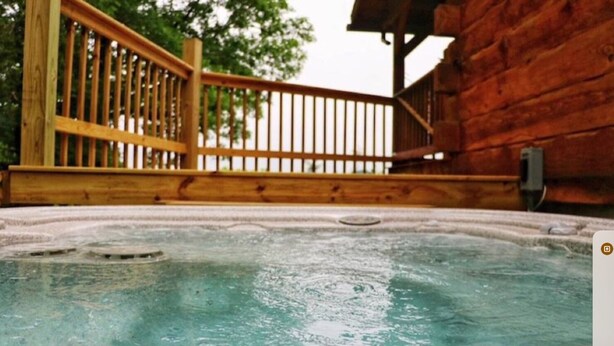 Ein Whirlpoolbereich mit Holzterrasse und einem Holzhaus im Hintergrund.