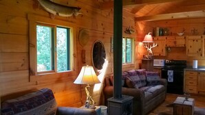 Ein gemütliches Blockhaus-Interieur mit einer Couch, einer Lampe, einem Kamin und Holzwänden.