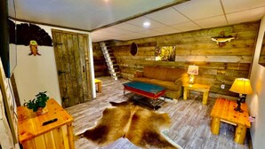 Ein rustikales Interieur mit einer Holzwand, einem Sofa, einem Couchtisch, einer Lampe und einem Bärenfell.