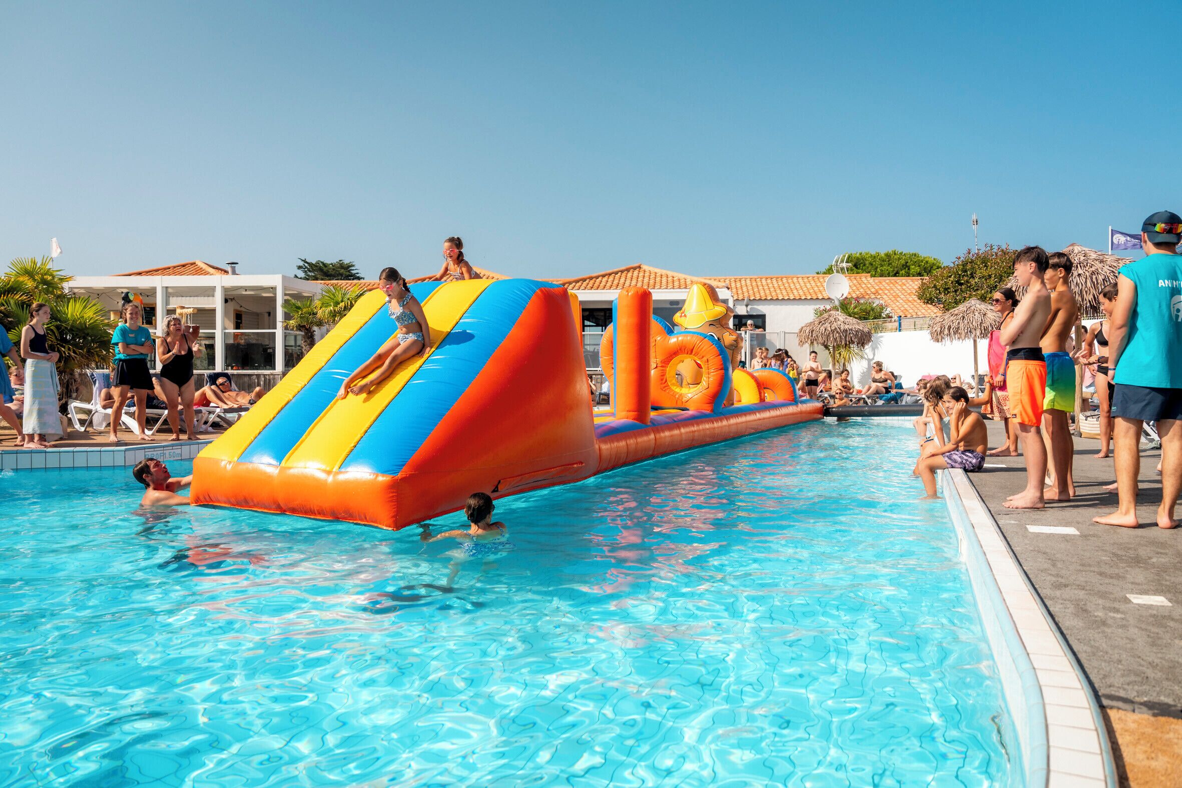 Une piscine avec des toboggans gonflables et des chaises longues.
