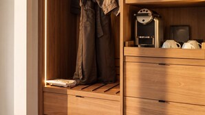 A wooden closet with a hanging rack, shelves, and a built-in coffee maker. - Arden Hotel (Vancouver)
