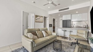 A modern living room with a sofa, a coffee table, and a bar area with stools. - Central South Brisbane 2-Bed with Stunning Views (South Brisbane)